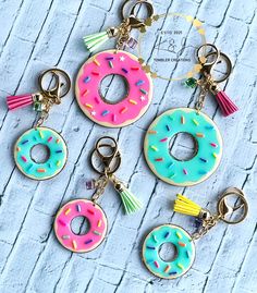 four donuts with tassels are hanging from key chains on a wooden surface