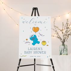 a welcome sign is on an easel next to a vase with flowers