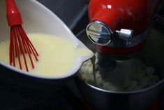 a red mixer mixing cream in a white bowl