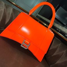 Authentic Balenciaga Bag Day Glow Orange Brand Spanking New Never Used **Missing Long Orange Strap*** Hourglass Small Handbag In Orange Shiny Box Calfskin, Aged Silver Hardware Dimensions : L9 X H5,9 X W3,9 Inch Shiny Box Calfskin Handbag Curvilinear Base One Handle Studded Magnet Closure Tone-On-Tone B Logo Hardware 1 Back Pocket 1 Inner Zipped Pocket Nappa Lambskin Lining Made In Italy Wipe With A Soft Cloth Material: 100% Calfskin Designer Orange Bags With Top Carry Handle, Orange Rectangular Shoulder Bag With Branded Hardware, Luxury Orange Bags With Top Carry Handle, Orange Rectangular Bag With Branded Hardware, Orange Rectangular Bags With Branded Hardware, Designer Orange Satchel Shoulder Bag, Orange Top Handle Bag With Dust Bag, Designer Orange Rectangular Bag, Designer Orange Rectangular Bags