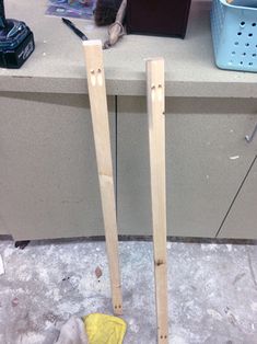 two pieces of wood sitting on top of a counter next to a blue basket and scissors