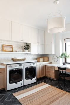 a kitchen with white cabinets and black flooring next to a washer and dryer