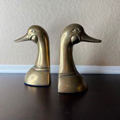 two brass ducks sitting on top of a wooden table