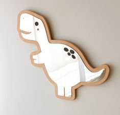 a wooden dinosaur shaped wall hanging on the wall