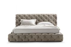 an upholstered bed with white sheets and pillows