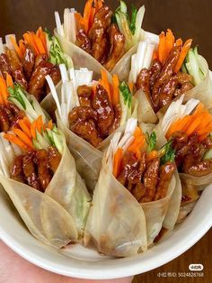 a plate filled with dumplings covered in meat and veggies on top of lettuce