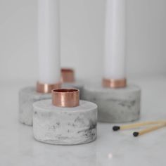 marble candlestick holders with copper rims on a white countertop next to matches