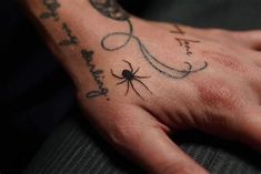 a person's hand with a spider tattoo on it and the word love written in cursive writing