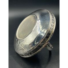 an antique silver plate on a black surface with the lid open and it is empty