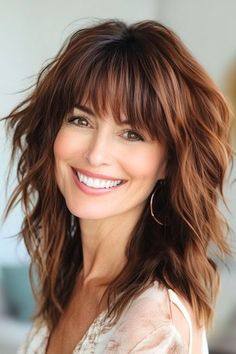 Save this pin for the best layered hair with bangs ideas. Get ready to rock a bohemian vibe with this tousled look. This cut is ideal for medium to thick hair, as it helps tame bulkiness and boost natural waves. Layered Hair With French Bangs, Medium Hairstyle Women With Bangs And Layers, Layered Brown Hair With Bangs, Layered Long Thick Hair, Wavy Hair With Bangs Hairstyles, Haircuts For Medium Length Hair With Bangs, Medium Length Haircut With Bangs And Layers, Hair Styles For Thick Medium Length Hair, 80s Rocker Hair Women