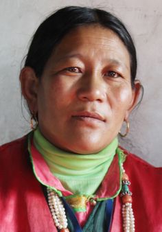 a woman in a red shirt and necklace with beads on her neck is looking at the camera