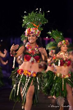 a woman in a hula skirt and headdress walking down the runway at night