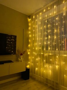 a living room with lights on the curtains and a television in front of a window