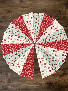 a red, white and blue quilted umbrella sitting on top of a wooden floor