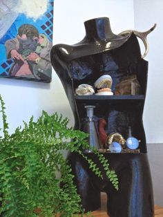 a black vase sitting on top of a wooden table next to a potted plant