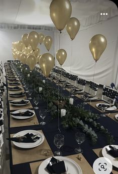 a long table set with plates, silverware and gold balloons