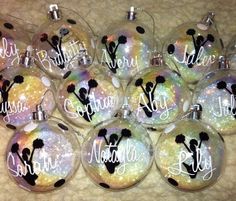 twelve personalized glass ornaments with names and silhouettes are shown on a table top