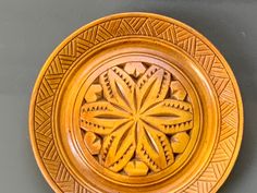 a decorative wooden plate with intricate designs on the front and back sides, sitting on a gray surface