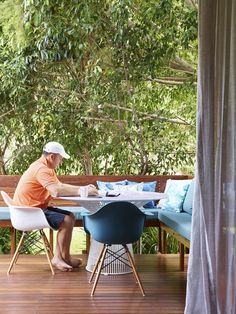 a man sitting at a table on top of a wooden deck next to a forest