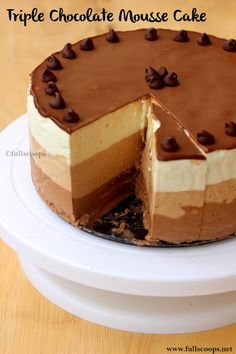 a triple chocolate mouse cake on a white plate with one slice cut out and ready to be eaten