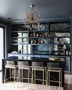 a bar with four chairs and a chandelier hanging from it's ceiling