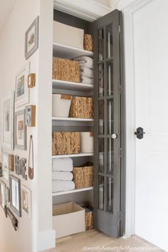 an open closet with baskets and pictures on the wall next to it's doors