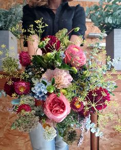 a woman is holding a large bouquet of flowers