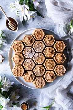 a white plate topped with waffles covered in powdered sugar next to flowers