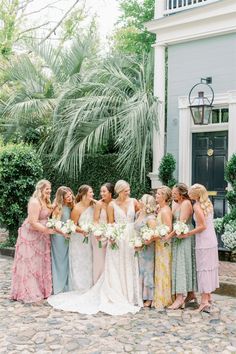 a group of women standing next to each other in front of a building with palm trees