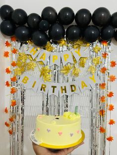 a person holding a birthday cake in front of balloons