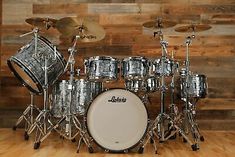 a silver drum set sitting on top of a hard wood floor next to a wooden wall