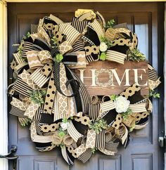 a wreath with the word home is hanging on a front door decorated with ribbons and flowers