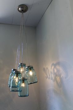 four mason jar chandelier hanging from the ceiling in a room with white walls