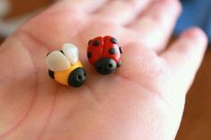 two tiny ladybug figurines are sitting on someone's hand,