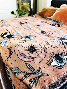 a bed covered in an orange blanket with flowers on it and a bee flying over the top