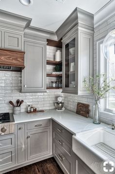 a kitchen with gray cabinets and white counter tops