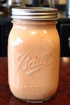 a mason jar filled with dressing on top of a wooden table