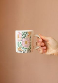 a person holding a coffee mug in their right hand and the other hand is pointing at it