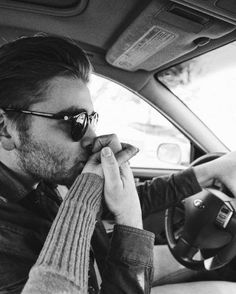 a man sitting in the driver's seat of a car while talking on a cell phone