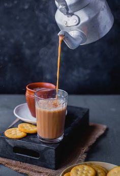 a person pouring coffee into a glass next to crackers