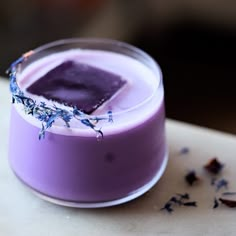 a purple substance in a glass with lavender sprinkles on the rim next to it