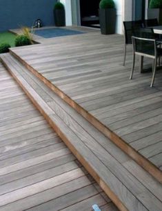 a wooden deck with steps leading up to an outdoor dining table and chairs on it