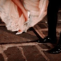 a man and woman dressed in formal wear standing next to each other on the sidewalk