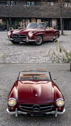 an old red convertible car parked in front of a large brick building with two windows