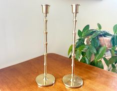 two brass candlesticks sitting on top of a wooden table