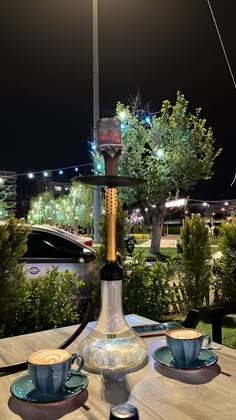 a table with two cups and saucers on it in front of a street light