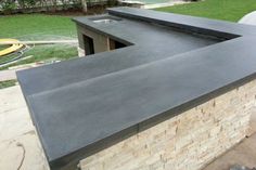 an outdoor kitchen with black granite counter tops and grilling area in the back yard