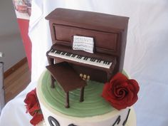 a cake that has a piano on top of it with a rose next to it