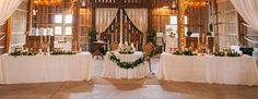 two tables with white tablecloths and greenery are set up for a wedding reception