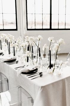 the table is set with white flowers and place settings